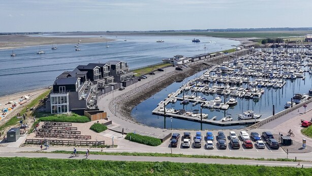Una marina con barcos, un edificio con balcón y un estacionamiento.