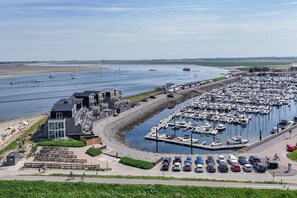 A marina with boats, a building with a balcony, and a parking area.