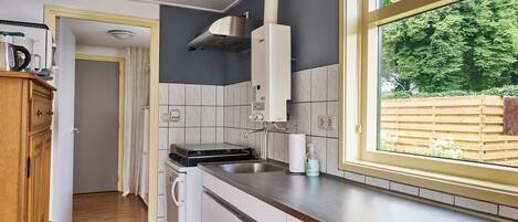 A compact kitchen with a window, a stove, and a sink.