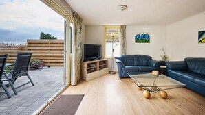 Una sala de estar con un sofá, televisión y una mesa de centro de vidrio.