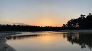 A calm lake at sunset with a forested shoreline. - Stay at This Beautiful Accommodation in De Kiel (De Kiel)