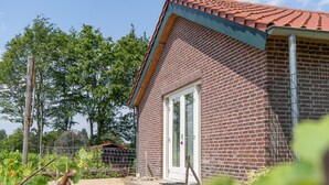 Un edificio in mattoni con tetto in tegole, una porta e un vialetto sterrato.