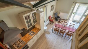 Cucina con piano cottura a gas, lavello e pensili. C'è un'area pranzo con tavolo e sedie.