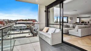 Eine moderne Wohnung mit Balkon, einem Wohnbereich mit Sofa und einer Essecke mit Küche.