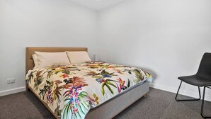 Ein Schlafzimmer mit einem Bett, einem Sessel und einer weißen Wand.