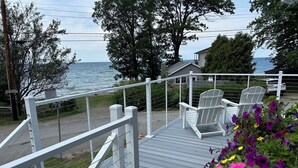 A wooden deck with white railings, a chair, and a flower planter.