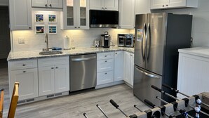 A modern kitchen with white cabinets, stainless steel appliances, and a built-in oven.