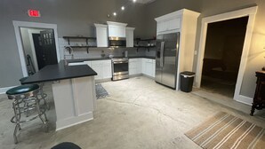 A kitchen with white cabinets, stainless steel appliances, and a black countertop. - Historic 2 bedroom steps off downtown square (Mountain Home)