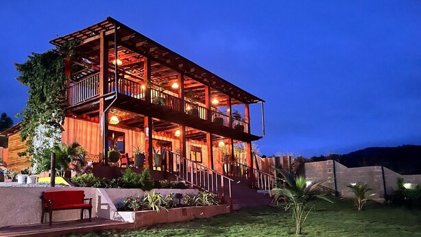 A two-story wooden building with a balcony, outdoor seating, and potted plants. - Seaview Cabana (Winneba)