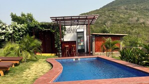 A swimming pool with a pergola and bar area, surrounded by grass and trees. - Seaview Cabana (Winneba)