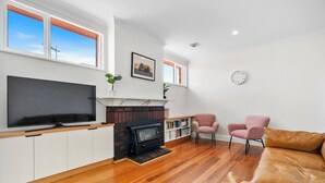 A living room with a TV, fireplace, and two pink chairs. - New Town Bungalow A Leafy Family Haven (New Town)