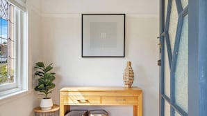 A room with a wooden console table, a potted plant, a framed picture, and a door with frosted glass panels. - New Town Bungalow A Leafy Family Haven (New Town)
