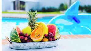A bowl of assorted fruits on a poolside table with a blue inflatable shark in the background. - Azores Luxury Residence

 (Borinquen)