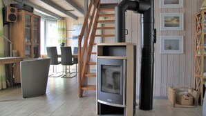 A cozy room with a built-in wood stove, a wooden staircase, and a dining area with a table and chairs.