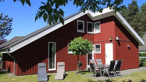 A red barn with a sloped roof, a door, and a small porch with a table and chairs.