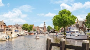 Een gracht met aangemeerde boten, houten steigers en traditionele gebouwen langs het water.
