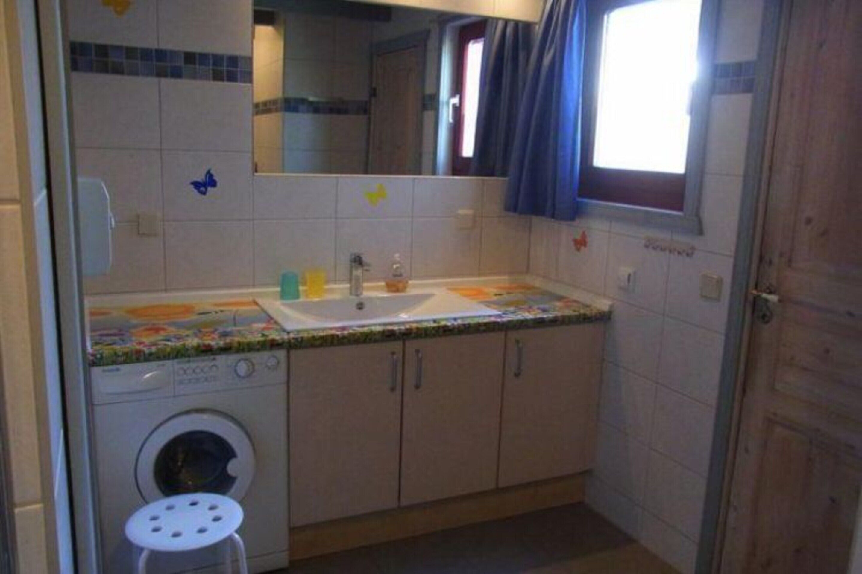 A compact bathroom with a washing machine, a sink, and cabinets.