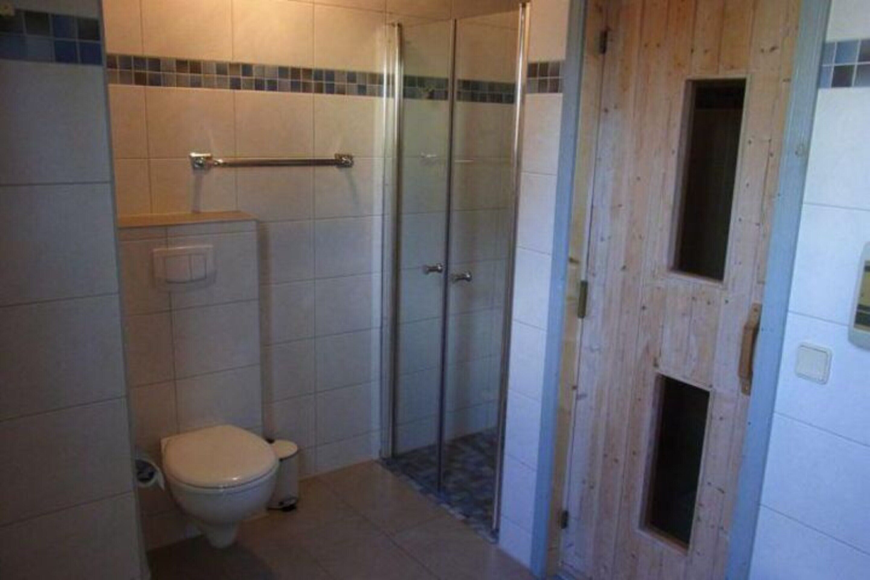 A bathroom with a toilet, a shower enclosure, and a wooden door.
