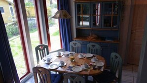 A dining area with a round table set for four, surrounded by chairs, and a blue cabinet with glass doors in the background. - Exklusives Skandinavisches Ferienhaus (Mirow)