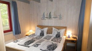 A bedroom with a wooden bed, two bedside tables, and a wall with a nautical-themed mural. - Exklusives Skandinavisches Ferienhaus (Mirow)