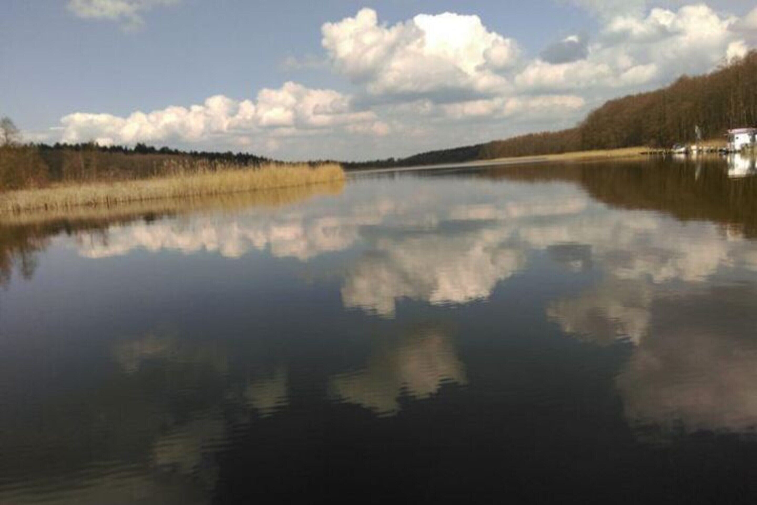 Een rustig meer met een heldere weerspiegeling van de lucht en bomen.