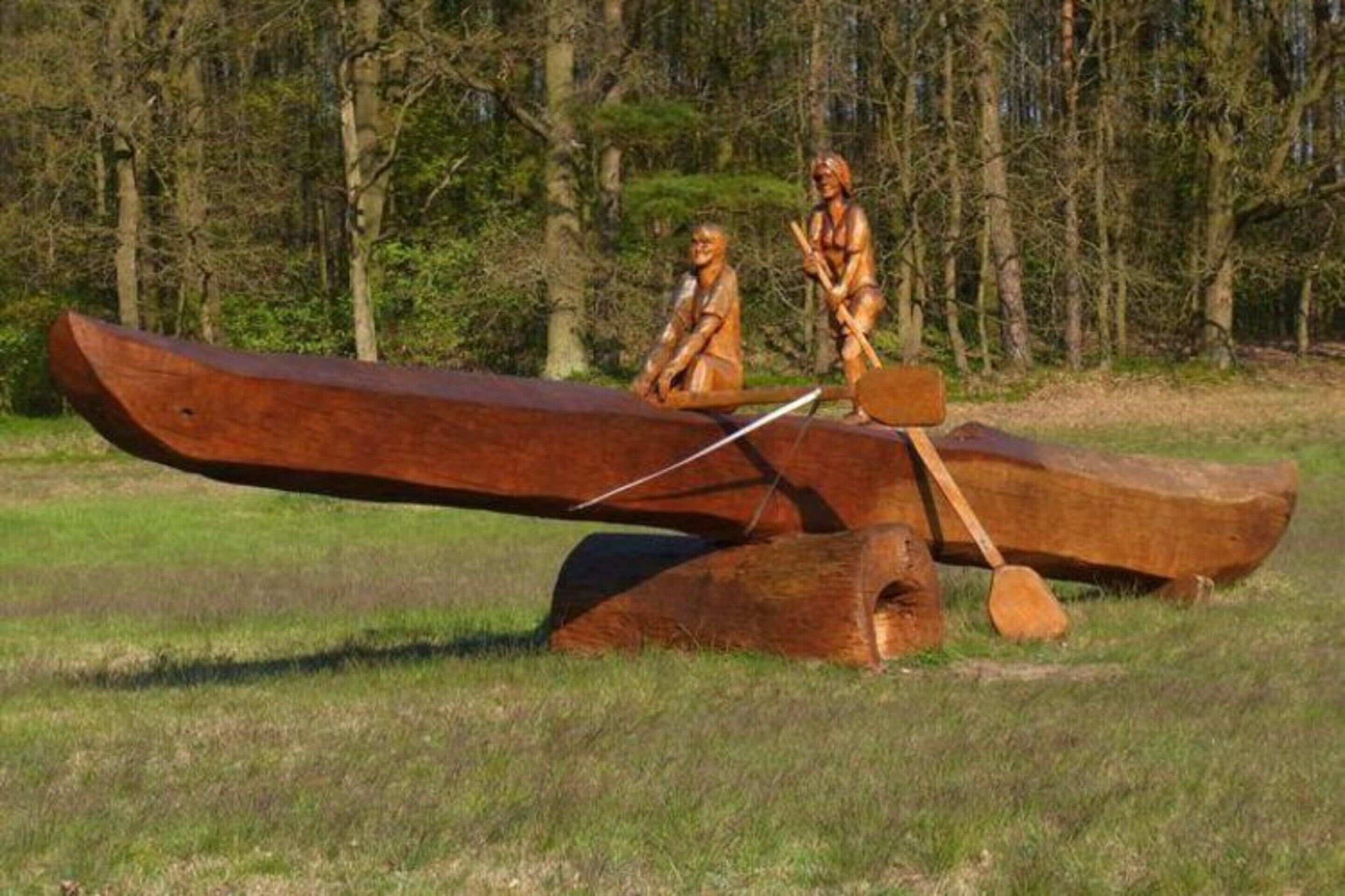 A wooden canoe balanced on a seesaw with two figures on it.