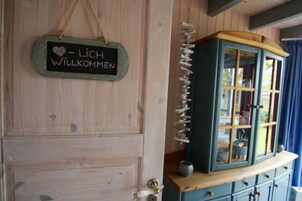 A wooden door with a chalkboard sign reading "LICH WILKOMMEN" and a blue cabinet with glass doors.