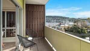 A balcony with a view of a cityscape, a wooden door, and two chairs. - Bellerive Quay Modern Living with Yacht Club Views (Bellerive)