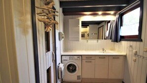 Een compacte, moderne badkamer met een geïntegreerde wasmachine, een wastafel en een spiegel.