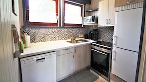 Een moderne keuken met vaatwasser, kookplaat, magnetron en koelkast.