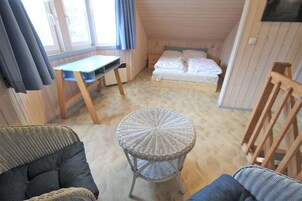 A small, cozy room with a bed, a desk, and a wicker chair.