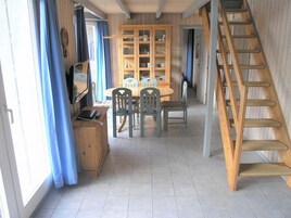 A dining area with a wooden table and chairs, a cabinet with glass doors, and a wooden ladder.