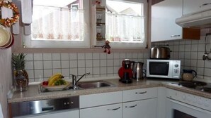 Et køkken med hvide skabe, en mikrobølgeovn, en elkedel og en vask.