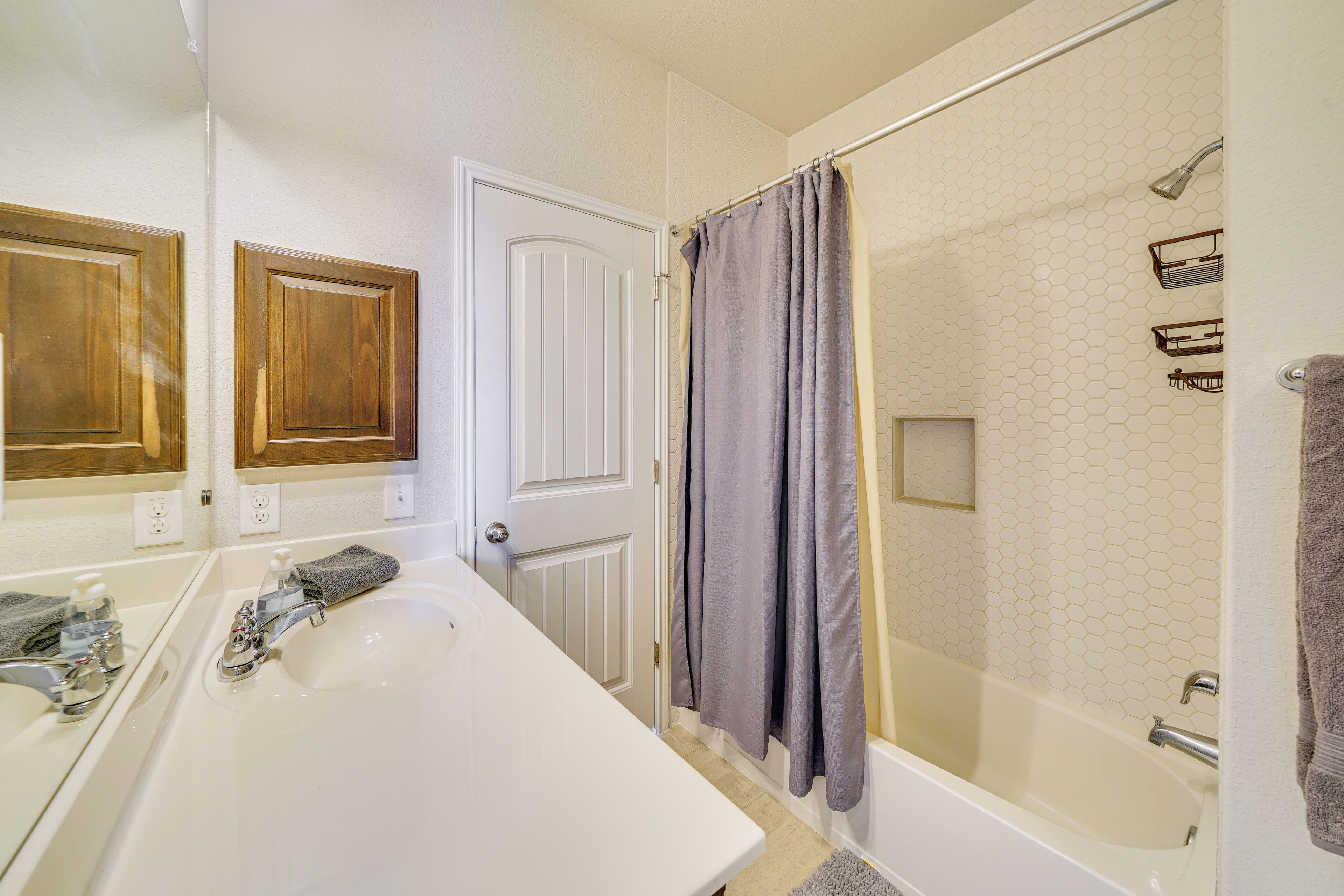 Une salle de bain avec une grande baignoire blanche, une douche avec une porte en verre et des meubles en bois au-dessus du lavabo.