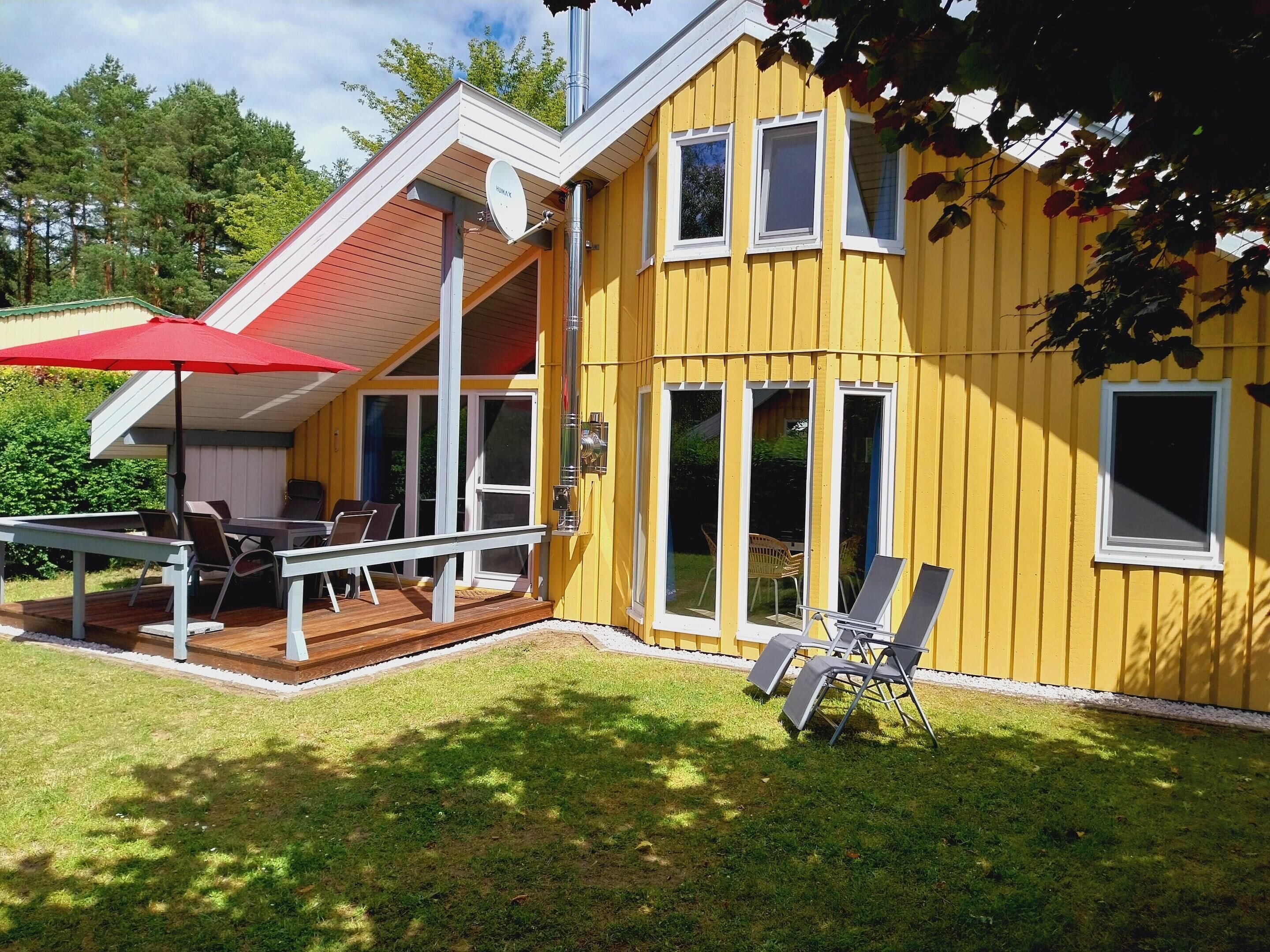 A yellow building with a deck, outdoor seating, and a satellite dish.