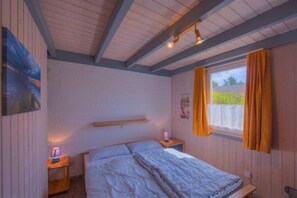 Cozy retreat with a sloped ceiling, wooden beams, and a window overlooking lush greenery.