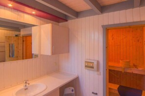 A bathroom with a sink and mirror, featuring a door to the right.