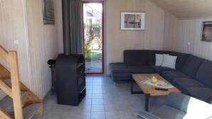 Un salon chaleureux avec un canapé gris foncé, une table basse en bois et un barbecue encastré.