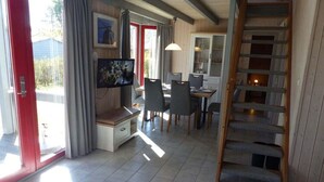 Un espace repas comprenant une table et des chaises, un téléviseur et un escalier.