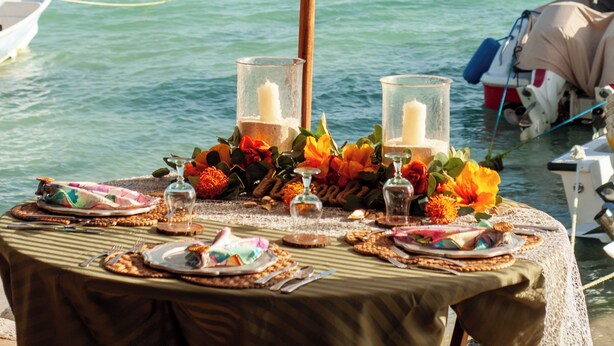 A table set for dining with a view of the sea and a boat in the background. - La Gotera (Los Roques)