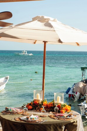 A table set for dining with a view of the sea and a boat in the background. - La Gotera (Los Roques)