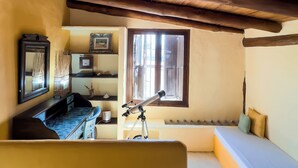 A cozy room with a wooden ceiling, a telescope, a bed, and a window. - La Gotera (Los Roques)