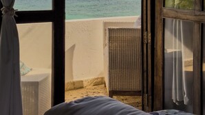 A room with a bed, a window with curtains, and a view of the sea. - La Gotera (Los Roques)