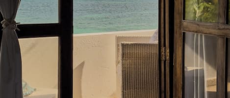 Una habitación con cama, ventana con cortinas y vista al mar.