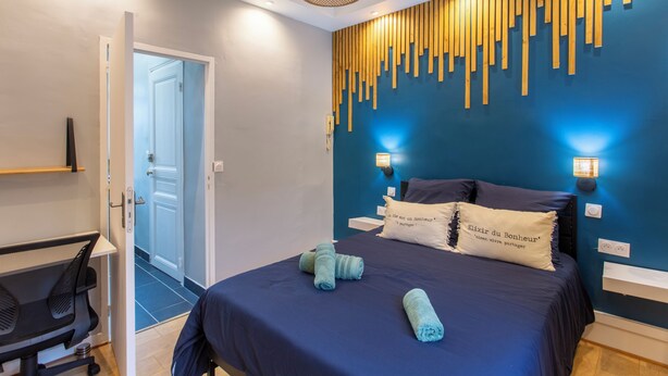 Un dormitorio moderno con una cama azul oscuro, un diseño de pared con listones de madera y dos lámparas de noche.