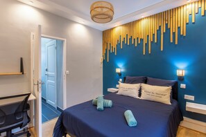 Un dormitorio moderno con una cama azul oscuro, un diseño de pared con listones de madera y dos lámparas de noche.