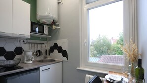 Una cocina equipada con microondas, cafetera y lavavajillas. Se ve una ventana con vistas a árboles y edificios.