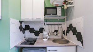 Una cocina compacta equipada con microondas, cafetera y lavamanos.
