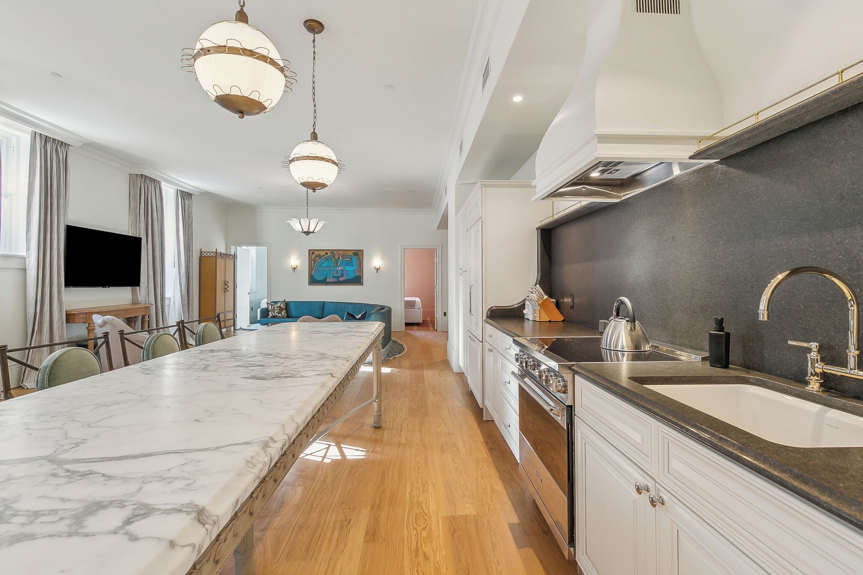 A modern kitchen with a marble countertop, stainless steel appliances, and pendant lighting.