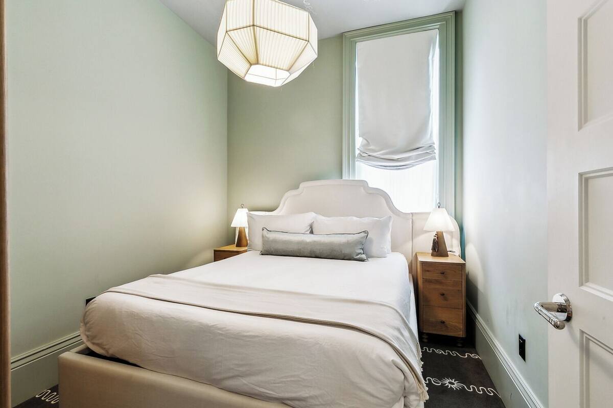 A neatly arranged bedroom with a bed, bedside tables, and a hanging light fixture.